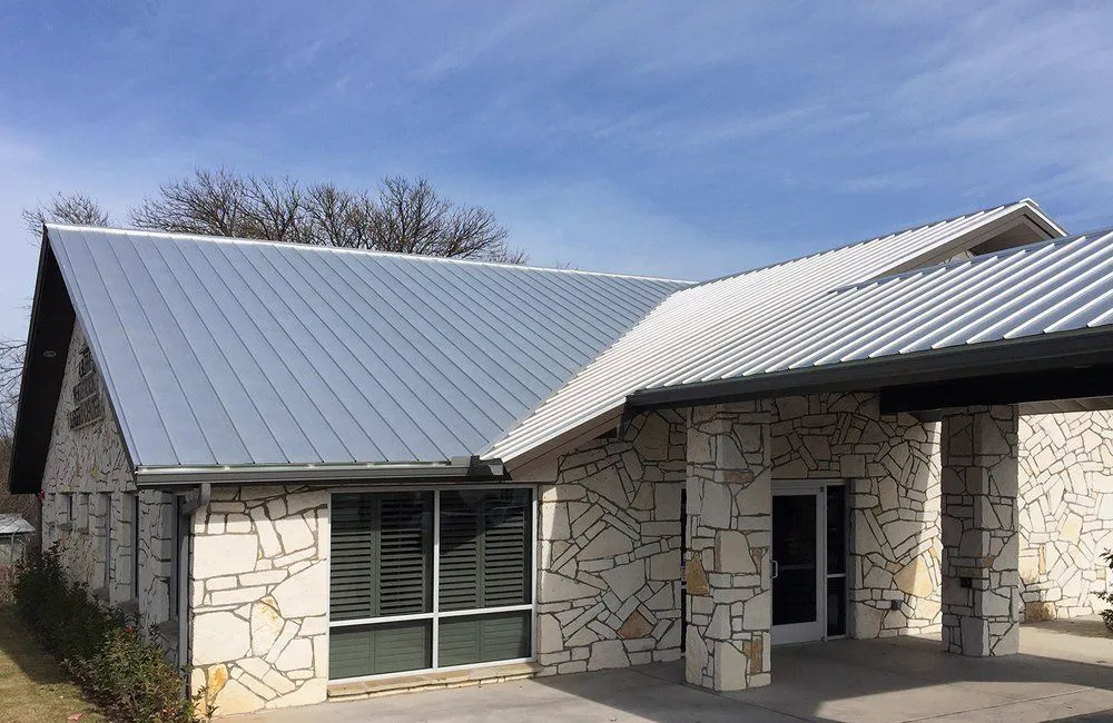 Limestone house under a silver standing-seam metal roof.