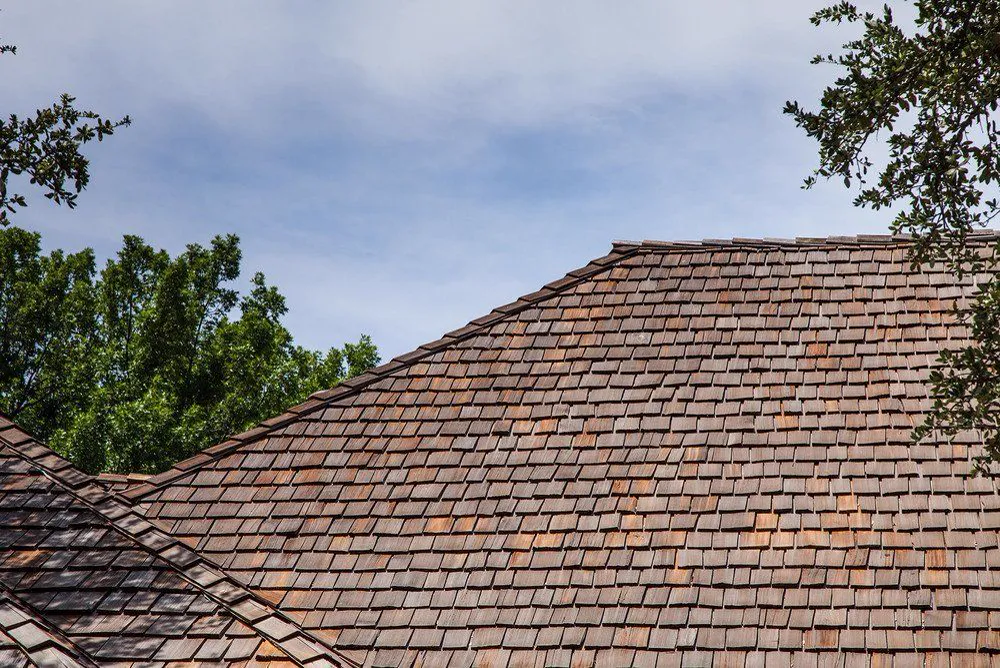 Weathered wood shake roof with layered hips.