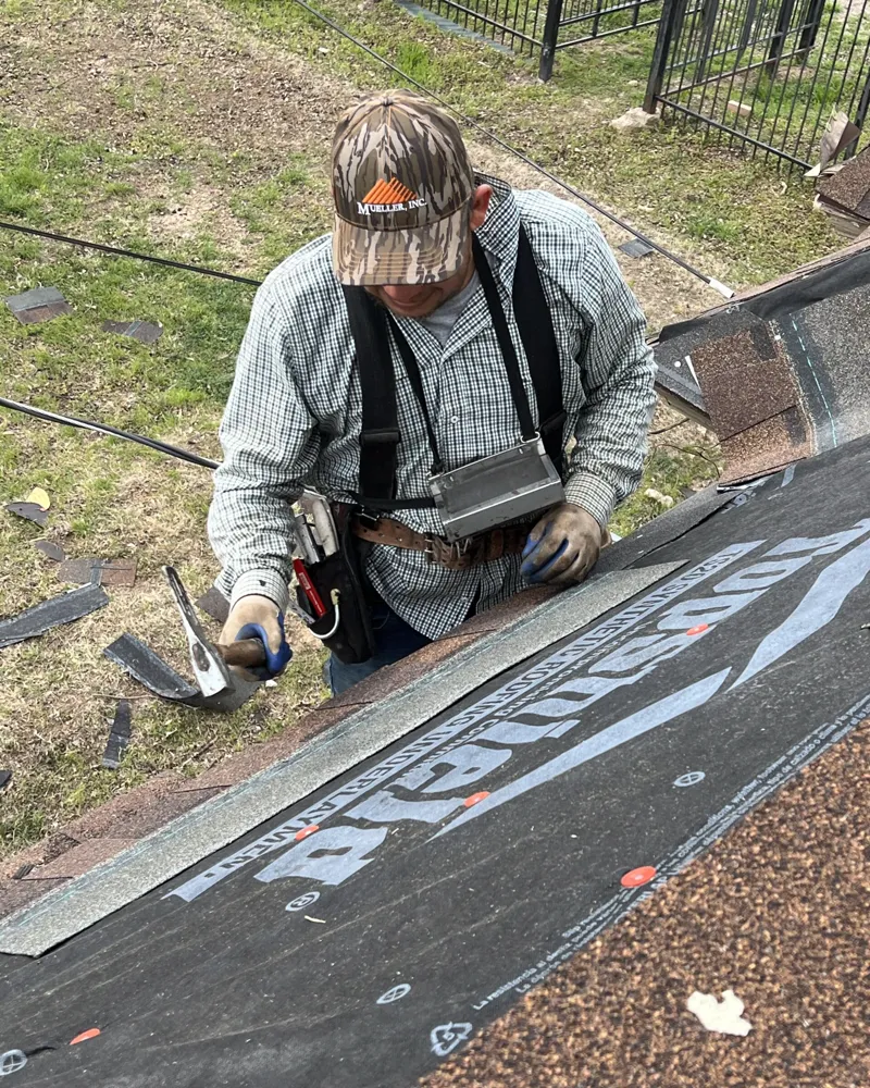 Roofer on fresh synthetic underlayment with a nail gun.
